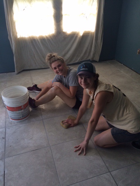 Madison Bick and Jenna Callahan work to finish a floor-tiling project at a home being restored by volunteers through Camp Restore - New Orleans.